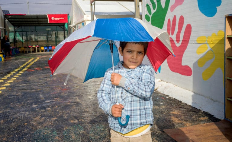 Gutt med paraply i en Redd Barna-barnehage i Zataari Camp, Jordan