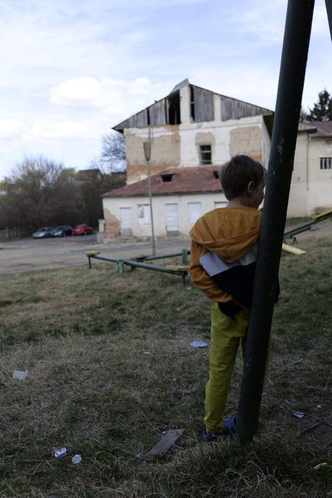 En gutt står og lener seg opp til et huskestativ utenfor et dagsenter for barn på flukt fra Ukraina