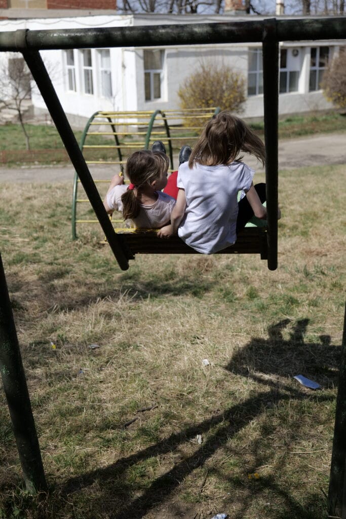 2 jenter i høy fart på en trehuske utenfor et dagsenter for barn på flukt fra Ukraina