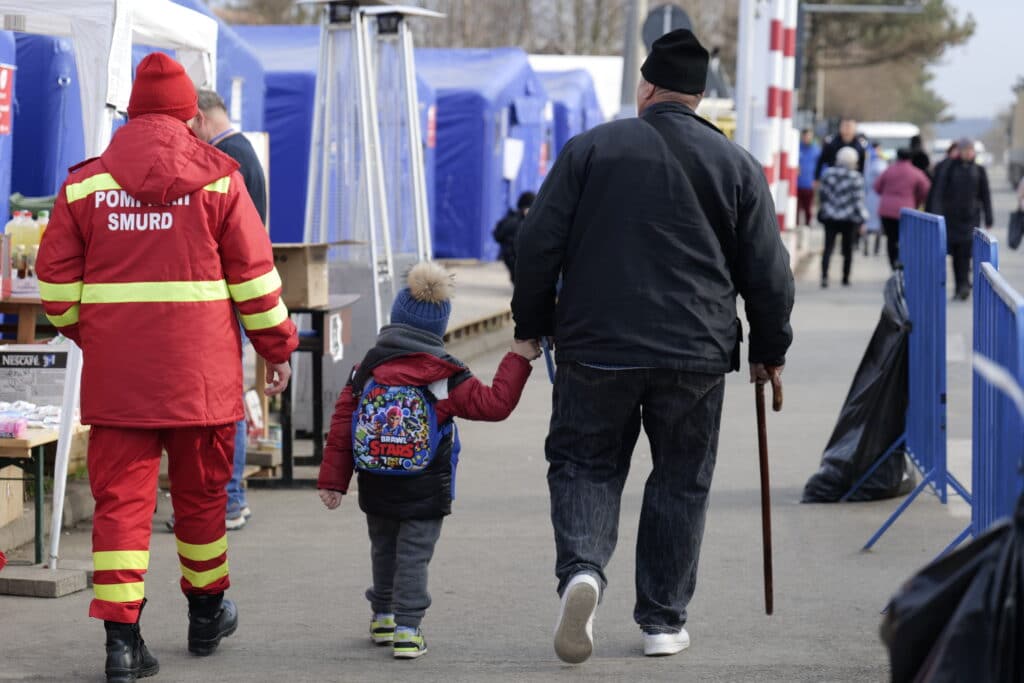 En mann med stokk og et barn med ryggsek ved grensepasseringen mellom Romania og Ukraina