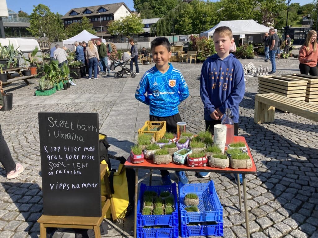To gutter står foran et bord med biler med gresstak.