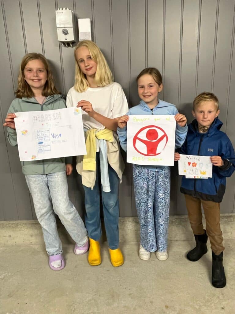 Fire glade barn som viser hjemmelagede plakater til basaren deres