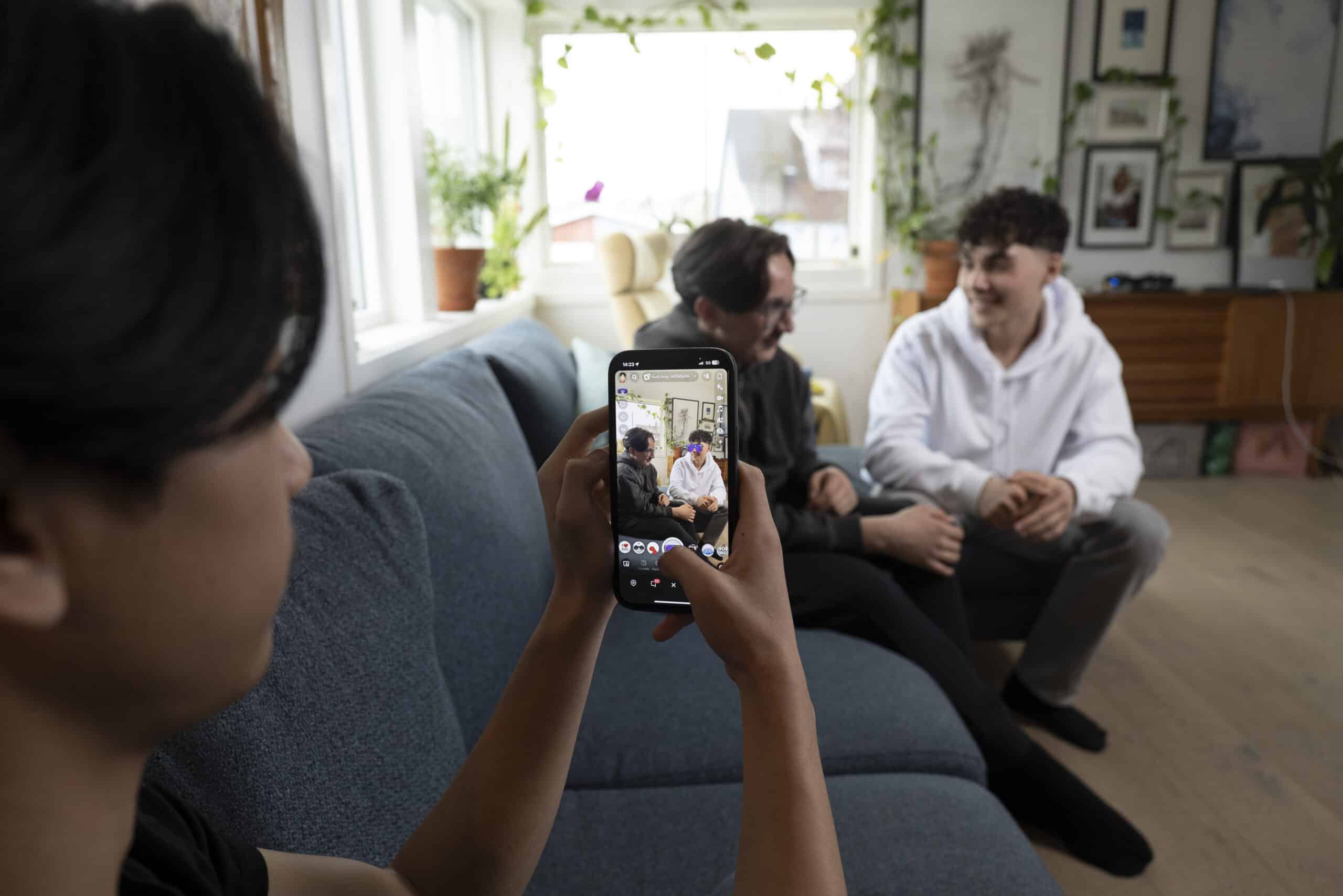 En ungdom tar bilde/snap av to andre ungdommer med snapchat-filter