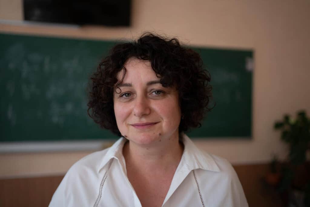 Olena i hvit skjorte smiler til kameraet