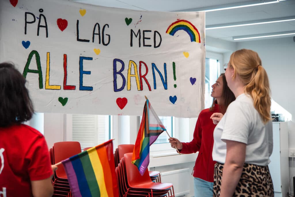Frivillige står sammen foran et skilt, der står det "på lag med alle barn!"