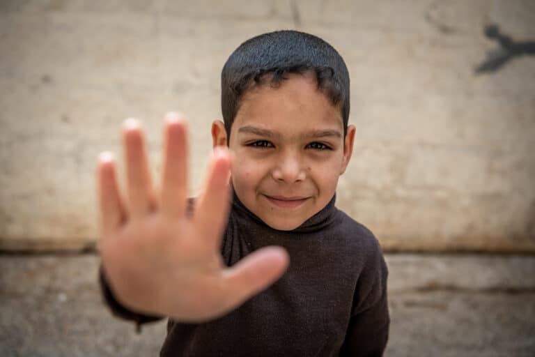 Rami på 7 år ser i kamera og holder ut hånden sin for å si "Stopp krig".