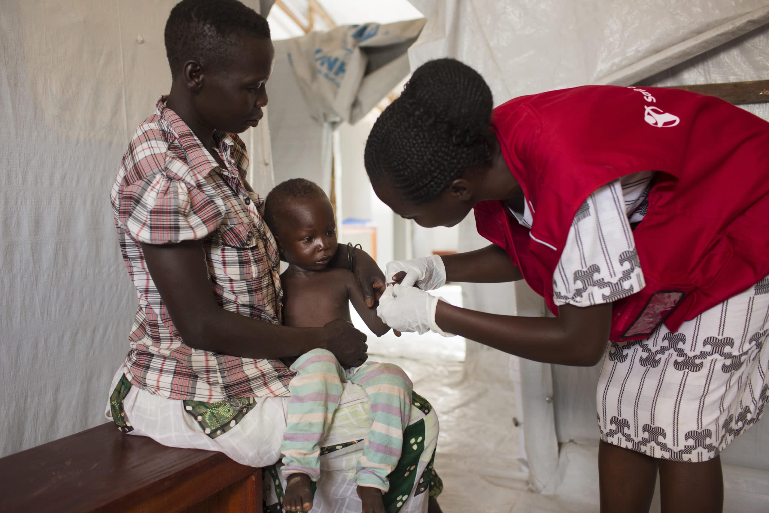 Foto av barn på ett år som testes for malaria av Redd Barna ansatt i Uganda.