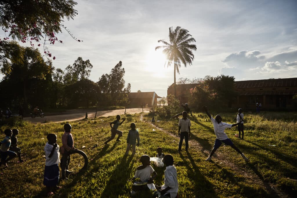 Foto av barn  i Kongo som leker utenfor  en skole. 