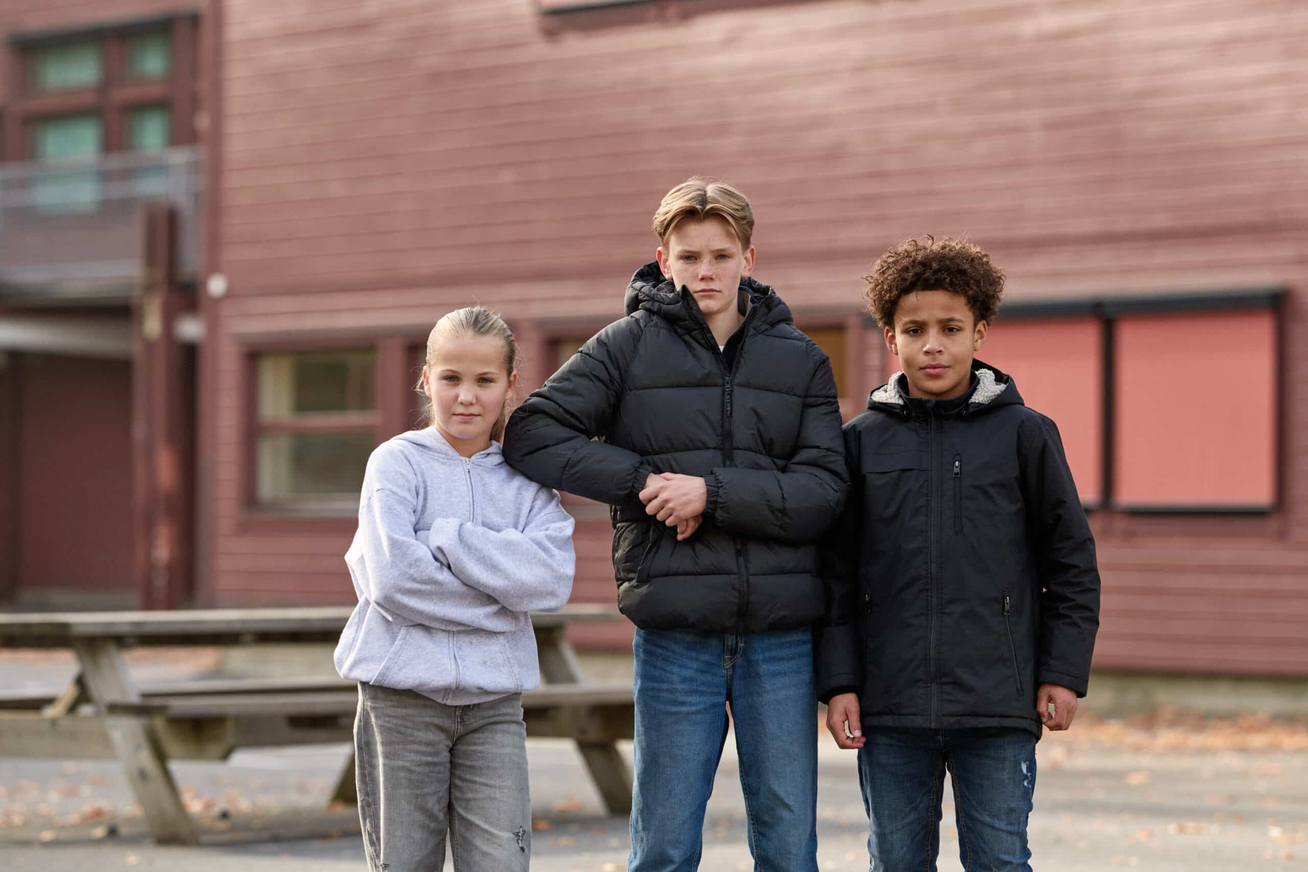 Tre ungdommer står og ser bestemt inn i kameraet
