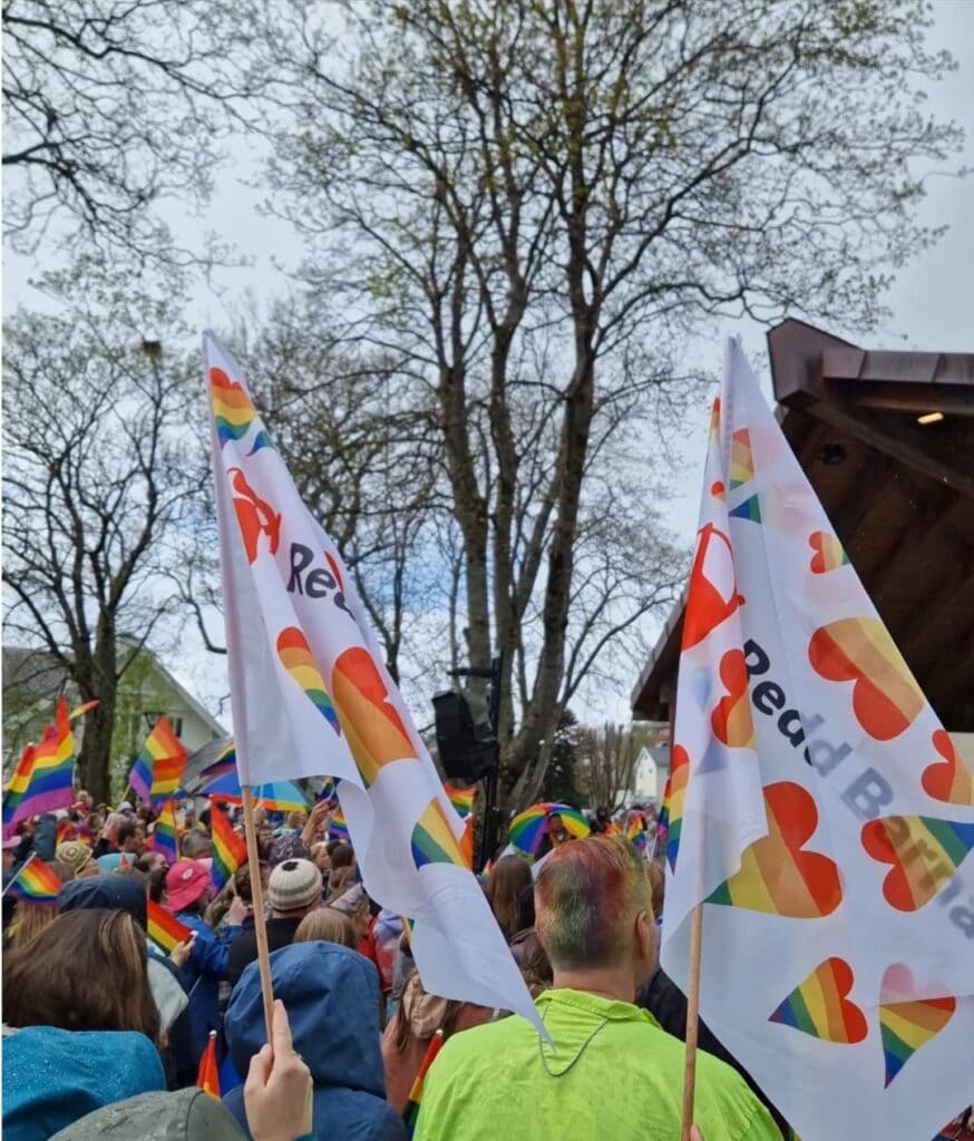 En stor samling mennesker med regnbueflagg og Redd Barna-flagg i Bergen