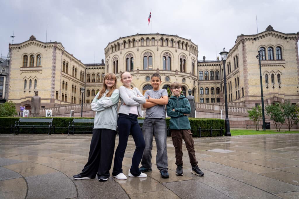 Fire ungdommer står med armene i kors foran Stortinget