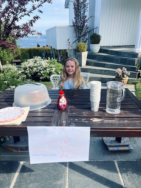 Jente sitter foran et bord og smiler