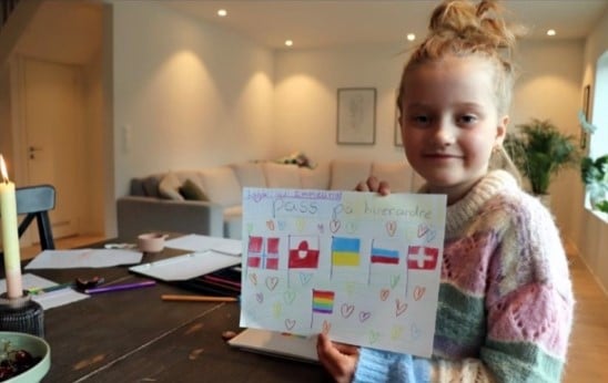Ei jente som smiler og holder opp en tegning.