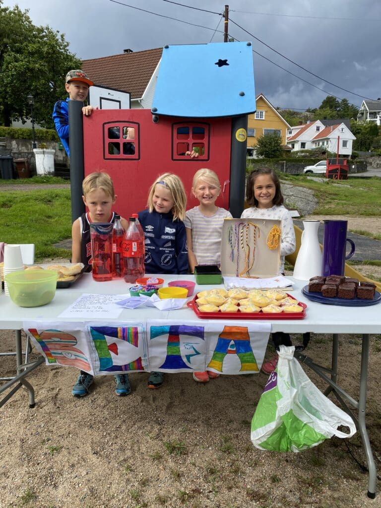 Basa på lekeplass med oppstilte barn som smiler