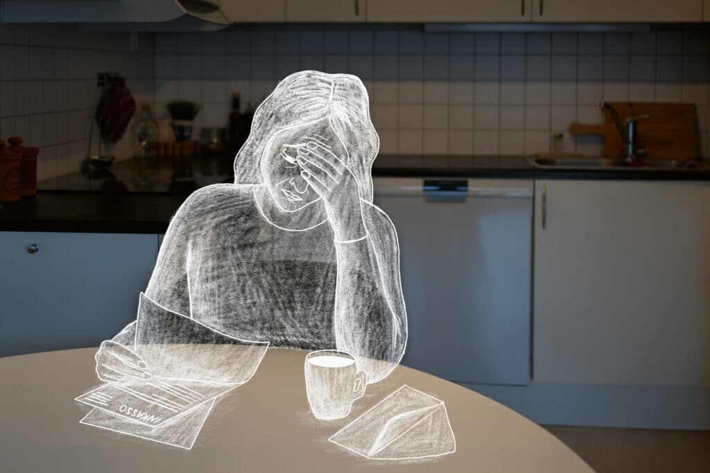 En illustrasjon av «Anne» som sitter og ser ned i regninger og inkassovarsel ved kjøkkenbordet.