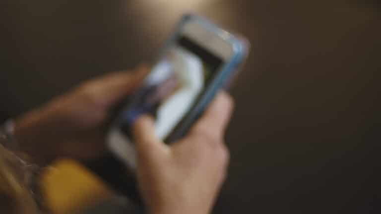 Et uskarpt bilde av en hånd som holder en mobiltelefon