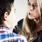 En mor ser og er i ferd med å kjefte på en ung gutt som er redd.