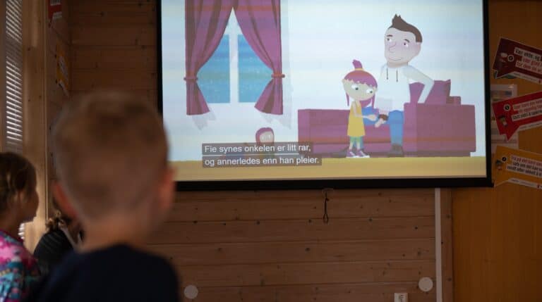 Bilde av barn som ser på NRK Supers temafilm om seksuelle overgrep hvor en tegnefilm viser en mann som viser penisen til et barn.