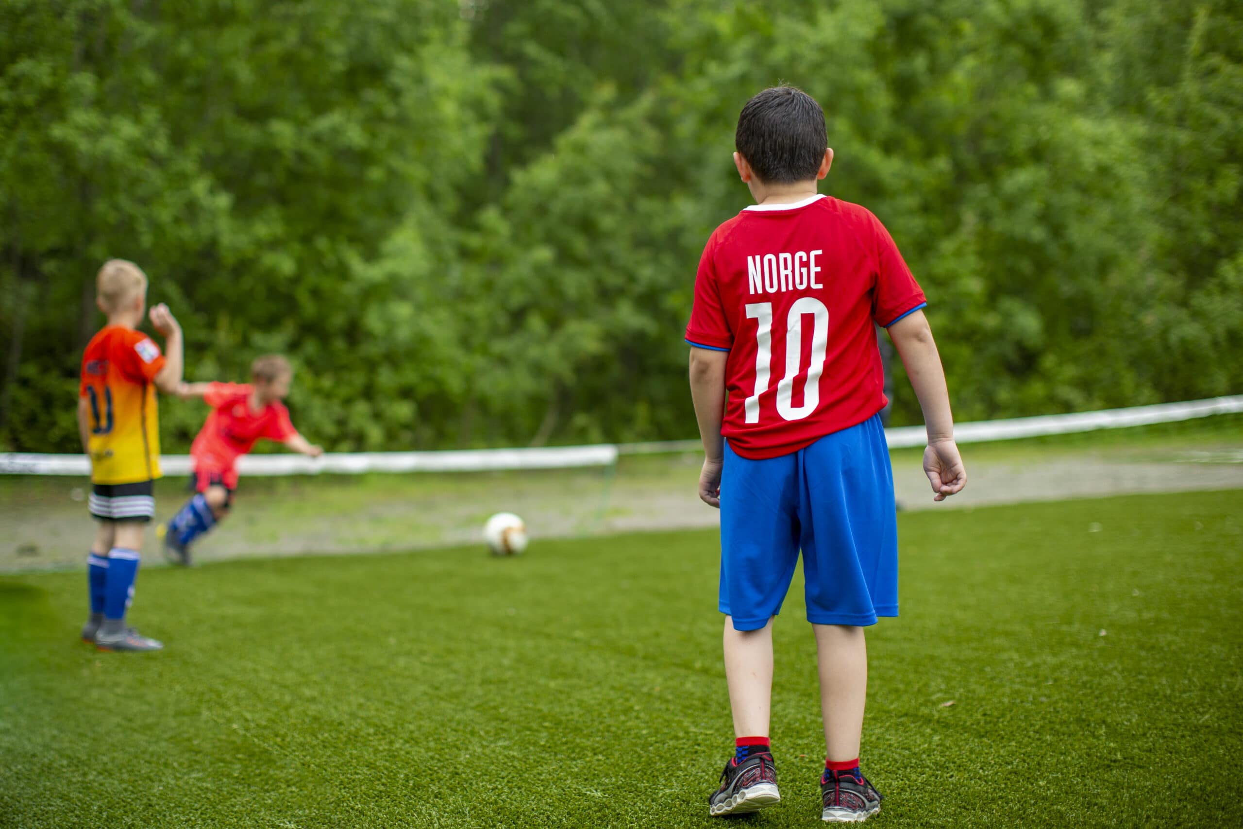 En gutt med draktnummer 10 står med ryggen til på fotballbanen