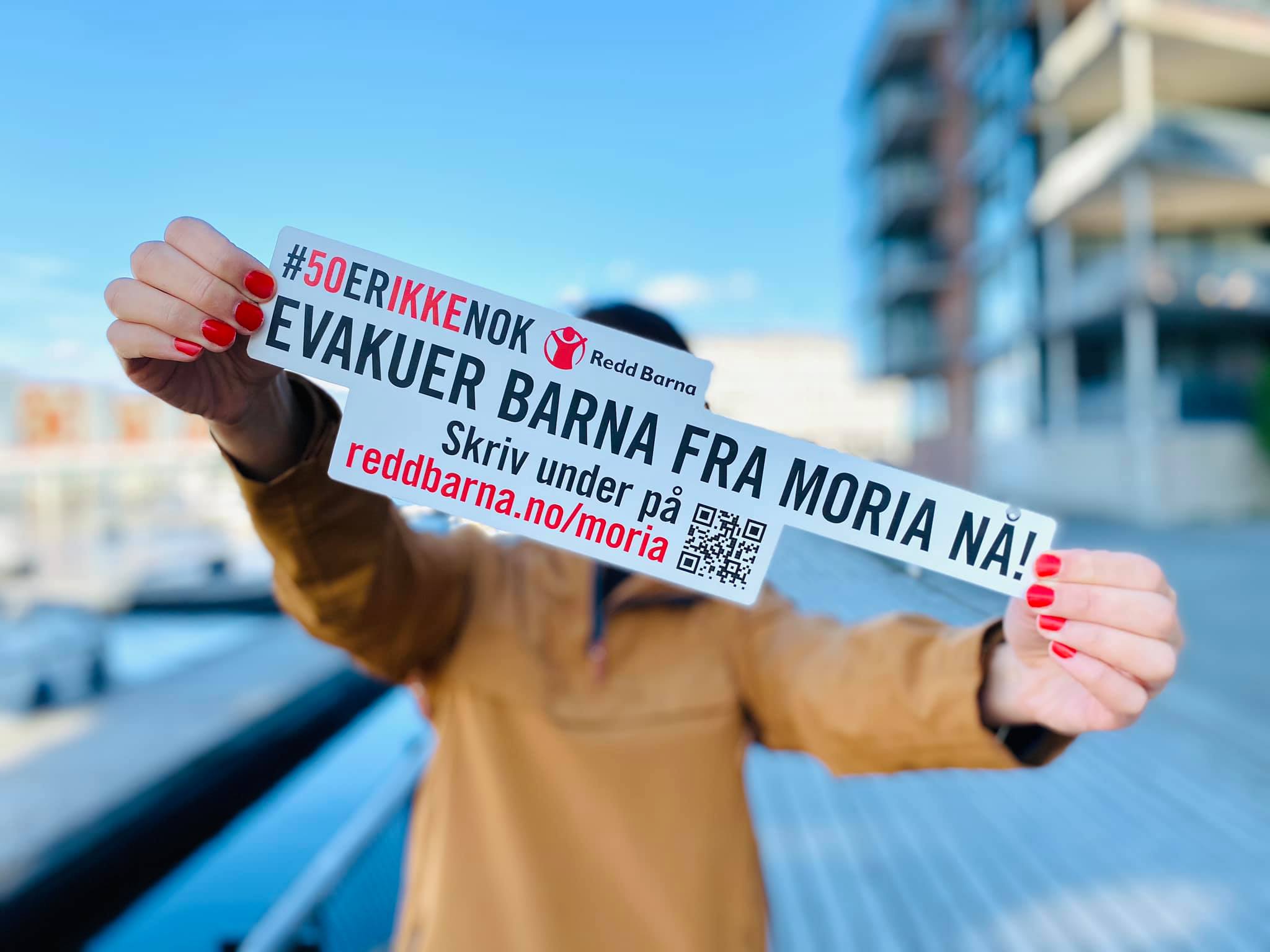 En person holder opp et skilt med en oppfordring om å evakuere barna fra Moria.