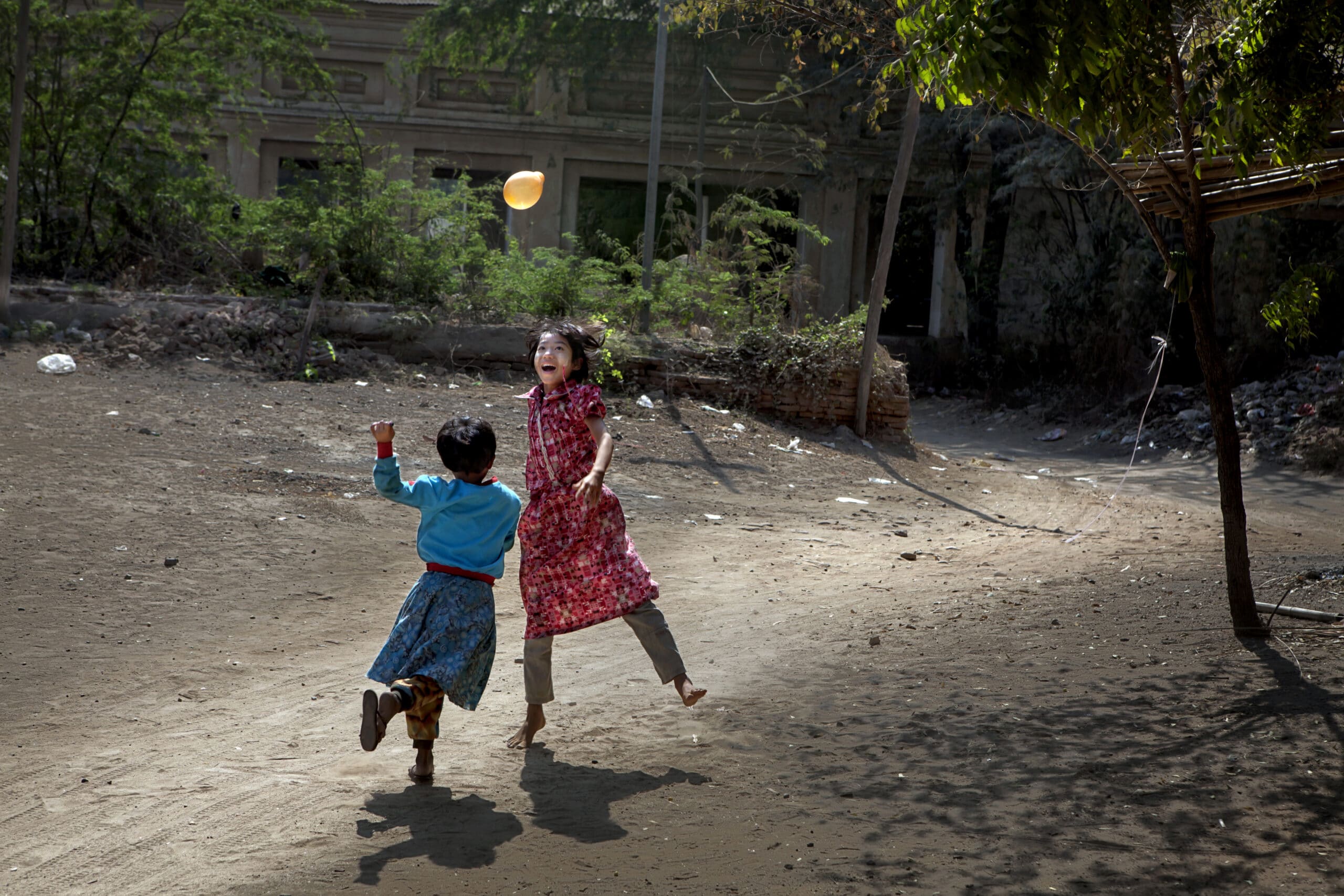 2 barn leker med en ballong ute i Myanmar