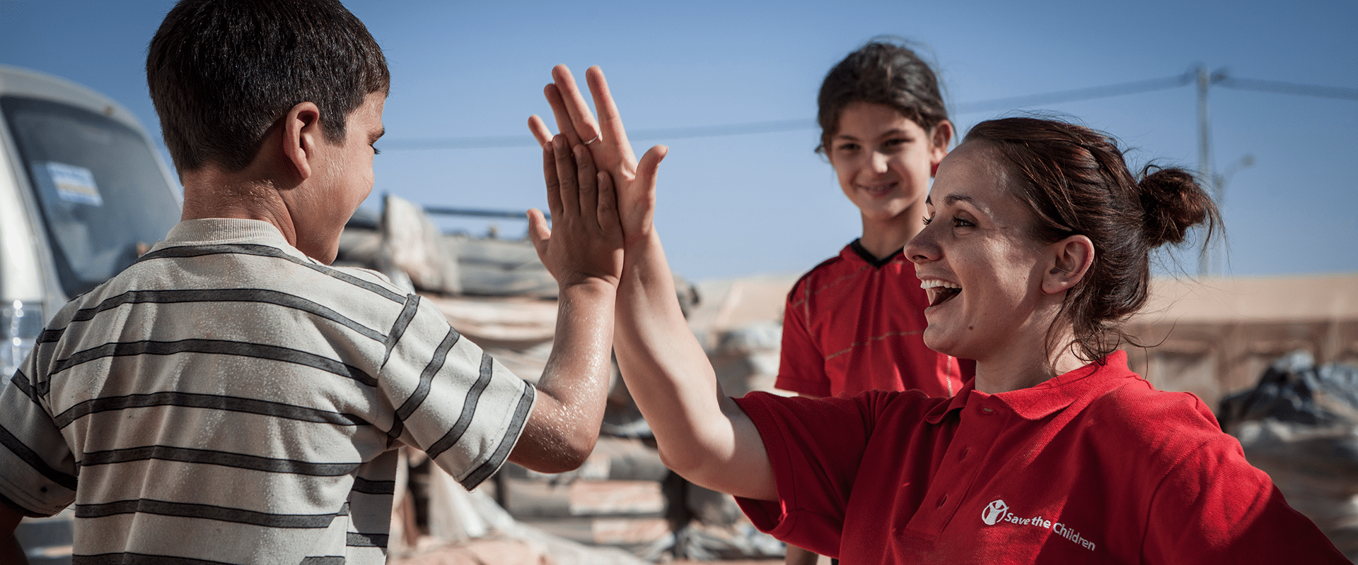 En Redd Barna-ansatt gir high-five med en gutt