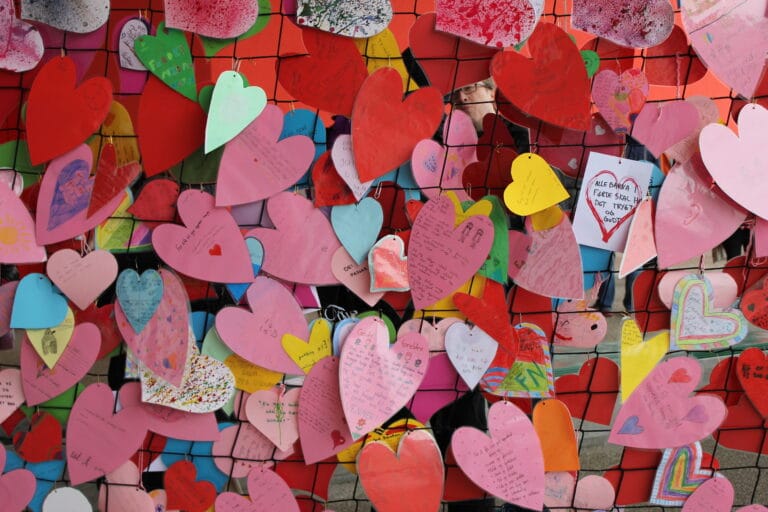 En vegg av papirhjerter i mange farger med meldinger fra barn