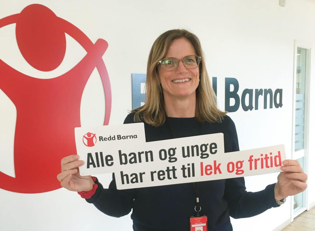 Generalsekretær i Redd Barna, Birgitte Lange, holder en plakat der det står Alle Barn og unge har rett til lek og fritid.