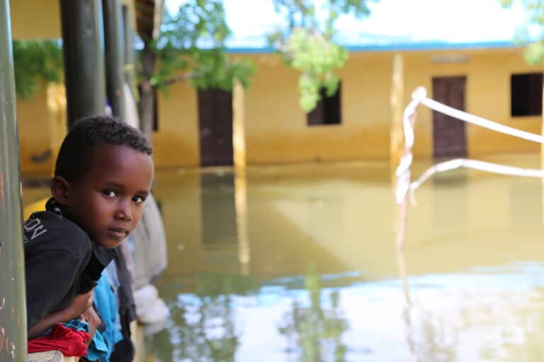 En gutt kikker ut av huset sitt i Somalia, på den oversvømte gaten utenfor