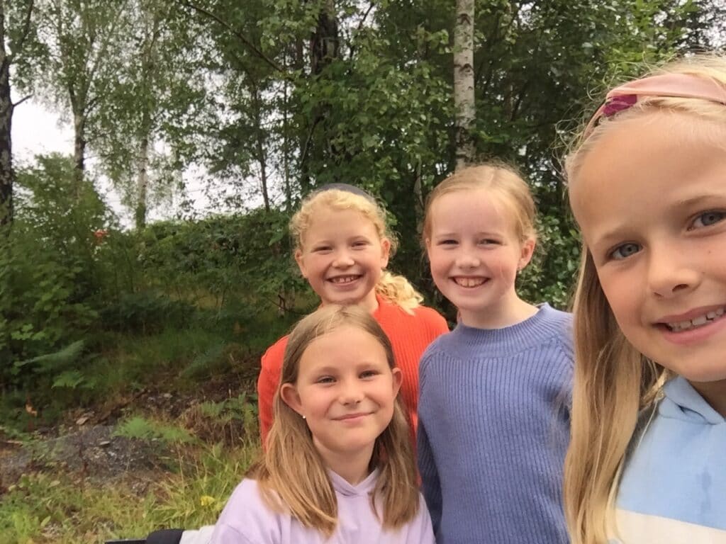 Fire jenter som smiler inn i bildet.