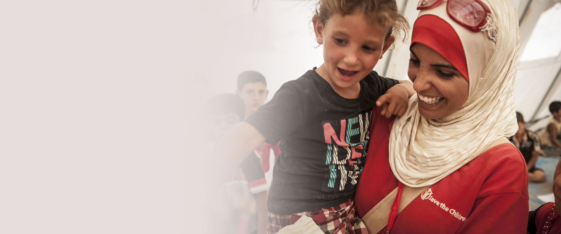 Redd Barna-ansatt holder et smilende barn i armene