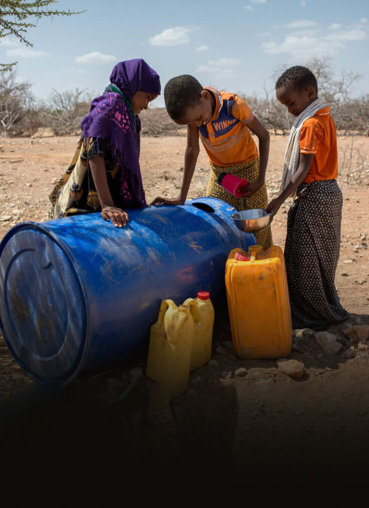 Tre somaliske barn henter vann fra en tønne