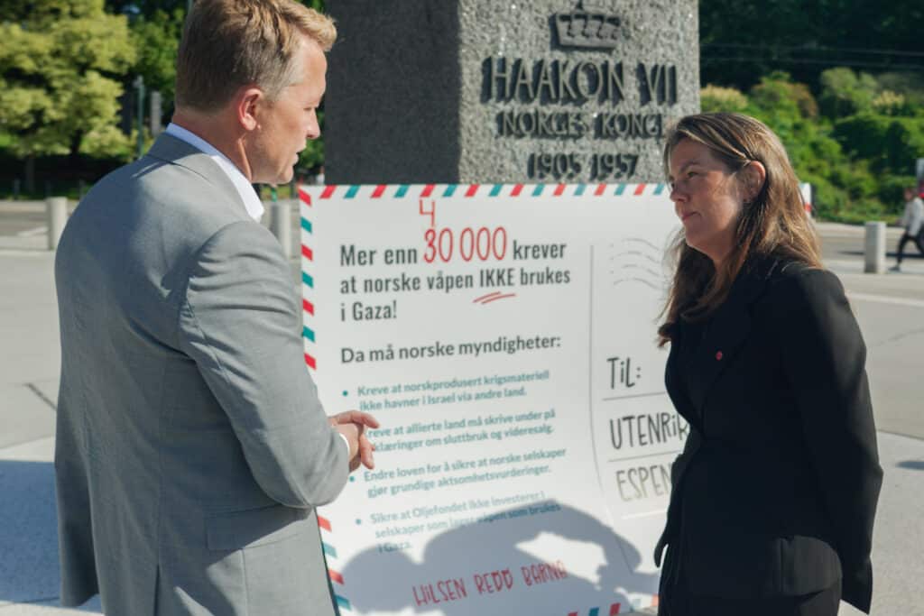 Foto av to personer som holder i et stort kort med underskrifter