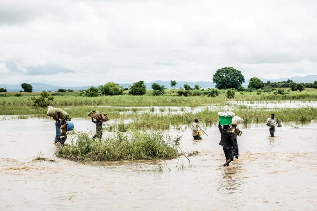 Fotografi av mennesker som går gjennom flomvann i Malawi.