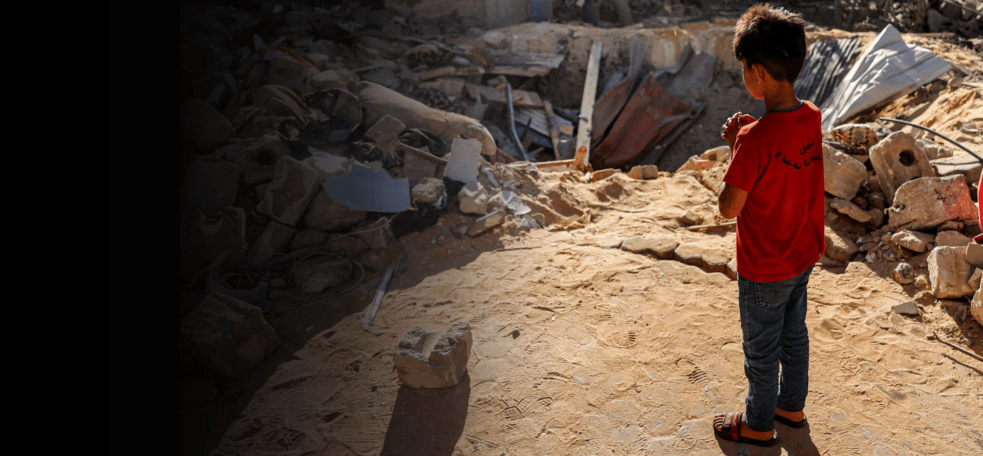 En gutt står foran et nedslagskrater der en bygning ble truffet av bomber i Rafah, Gaza