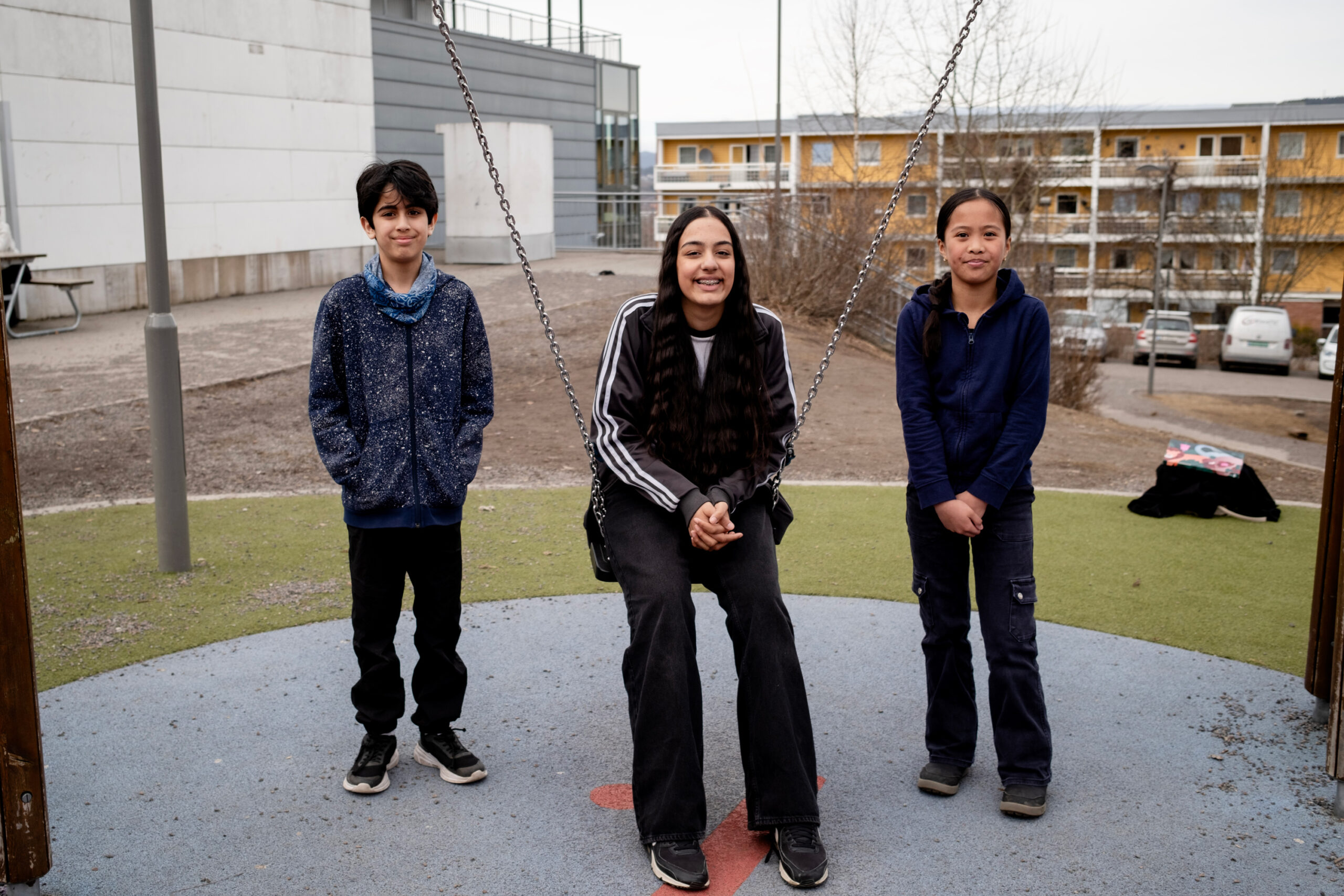 Mahnoor, Janine og og Adam sitter på uteplassen på Lindeberg skole.