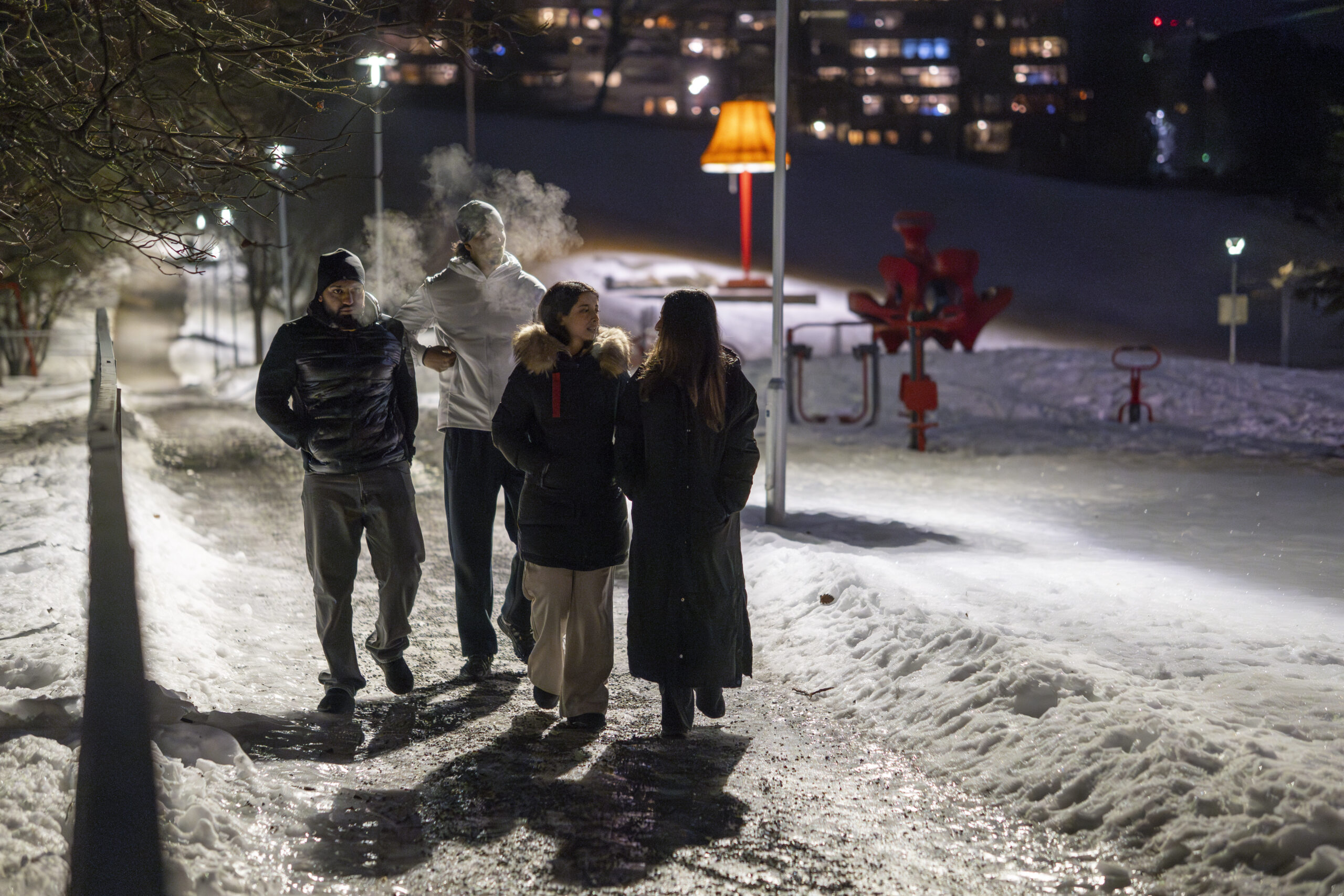 Hamza, Darker, Nour og Malaika går nedover veien forbi den store lampa og de høye blokkene på Haugenstua.