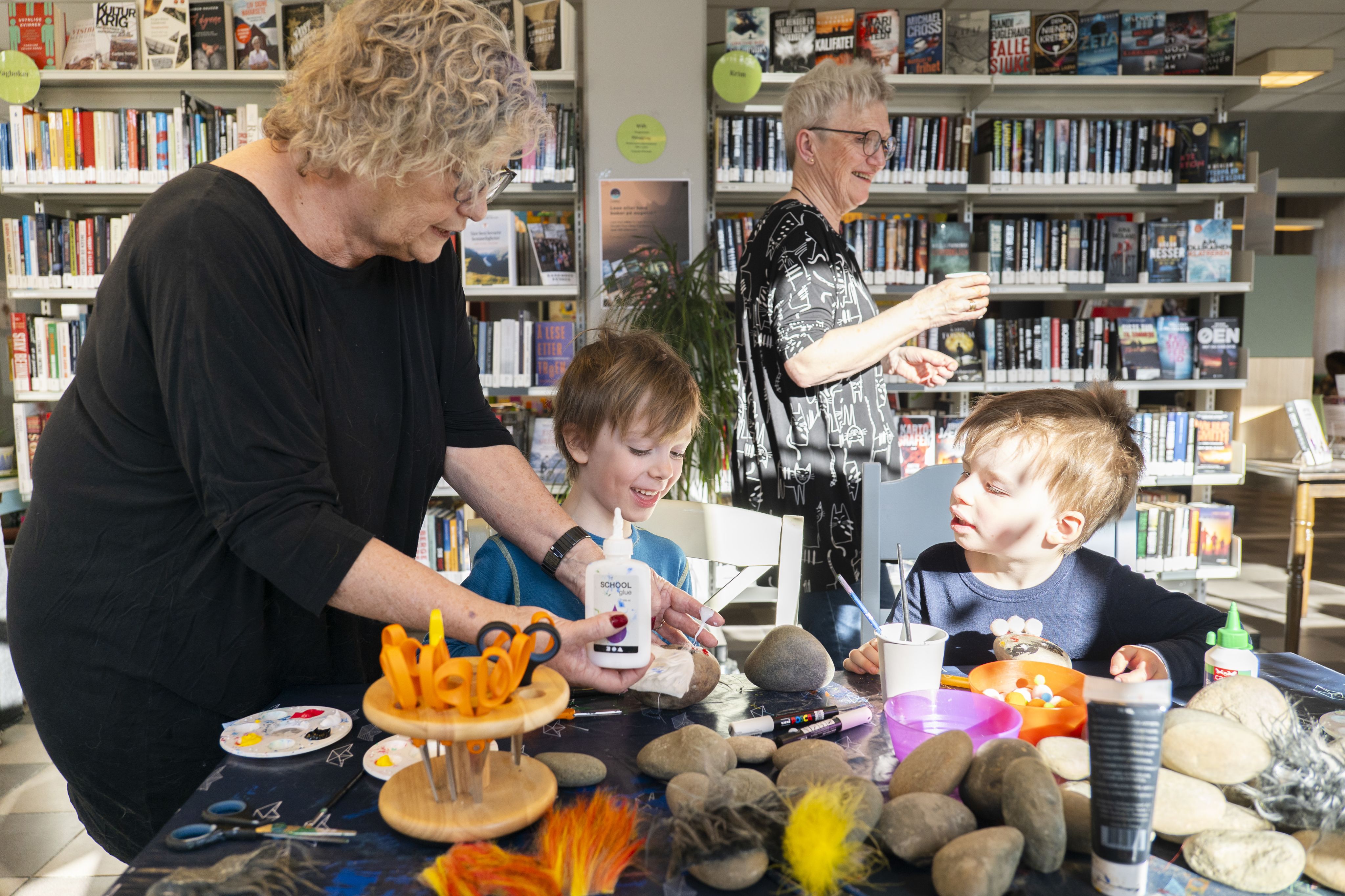Vigdis hjelper Matheo Gåsnes (5) og Daniel Reissmann (4) med å lime på trollhår på steiner. Foto..