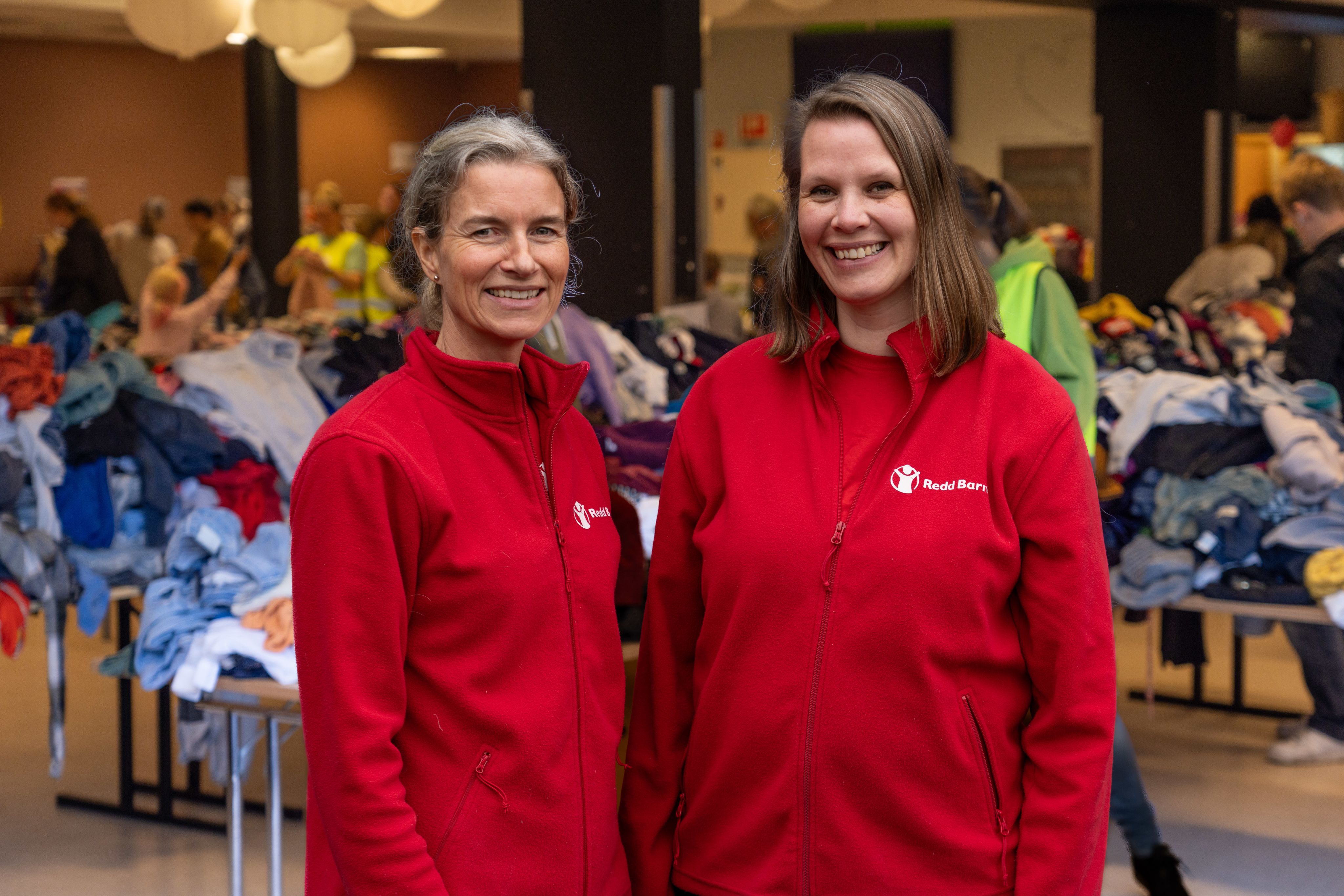 Gyrd og Kari i røde Redd Barna gensere står og smiler til kamera.