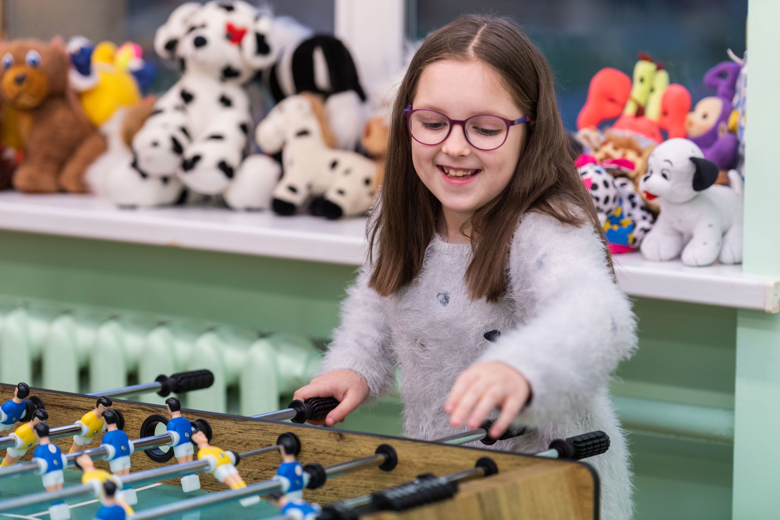 En jente smiler mens hun spiller foosball.