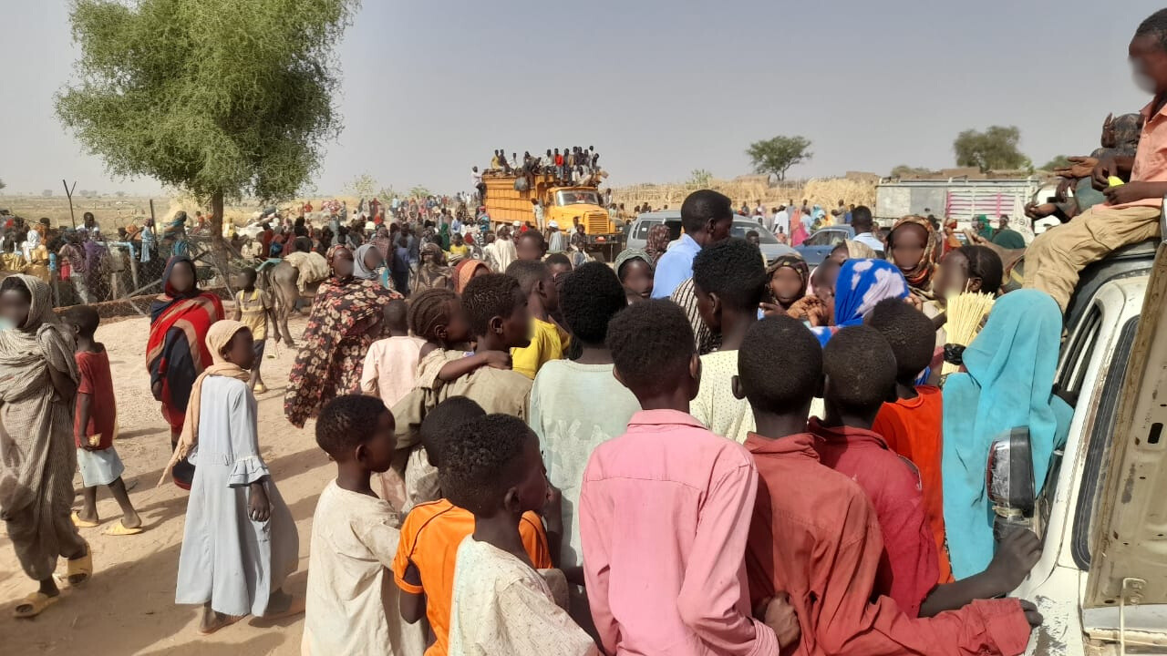 Fordrevne familier og barn samlet i et åpent område i Sudan.