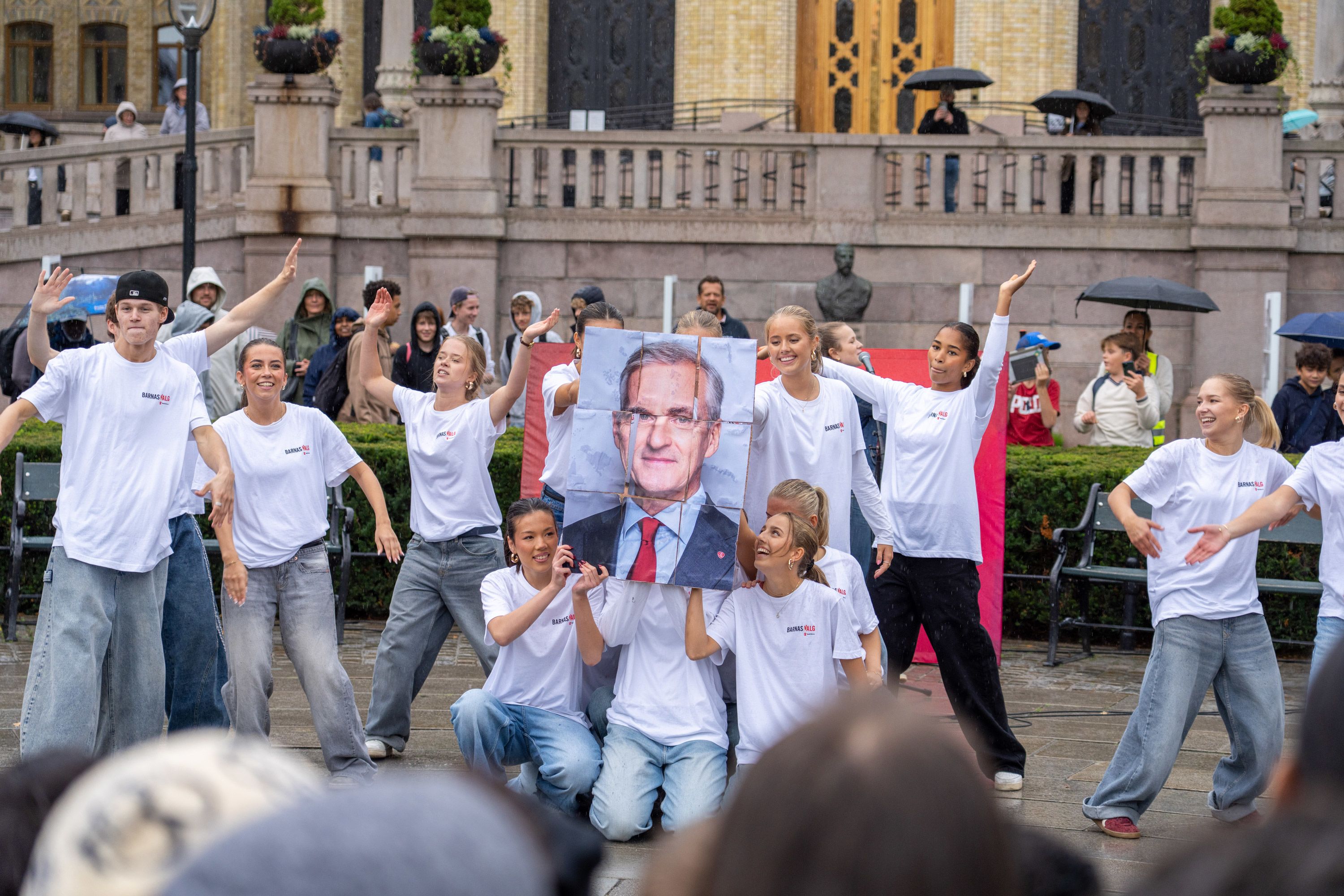 Ungdommer danser og holder opp en plakat av Jonas Gahr Støre foran Stortinget.