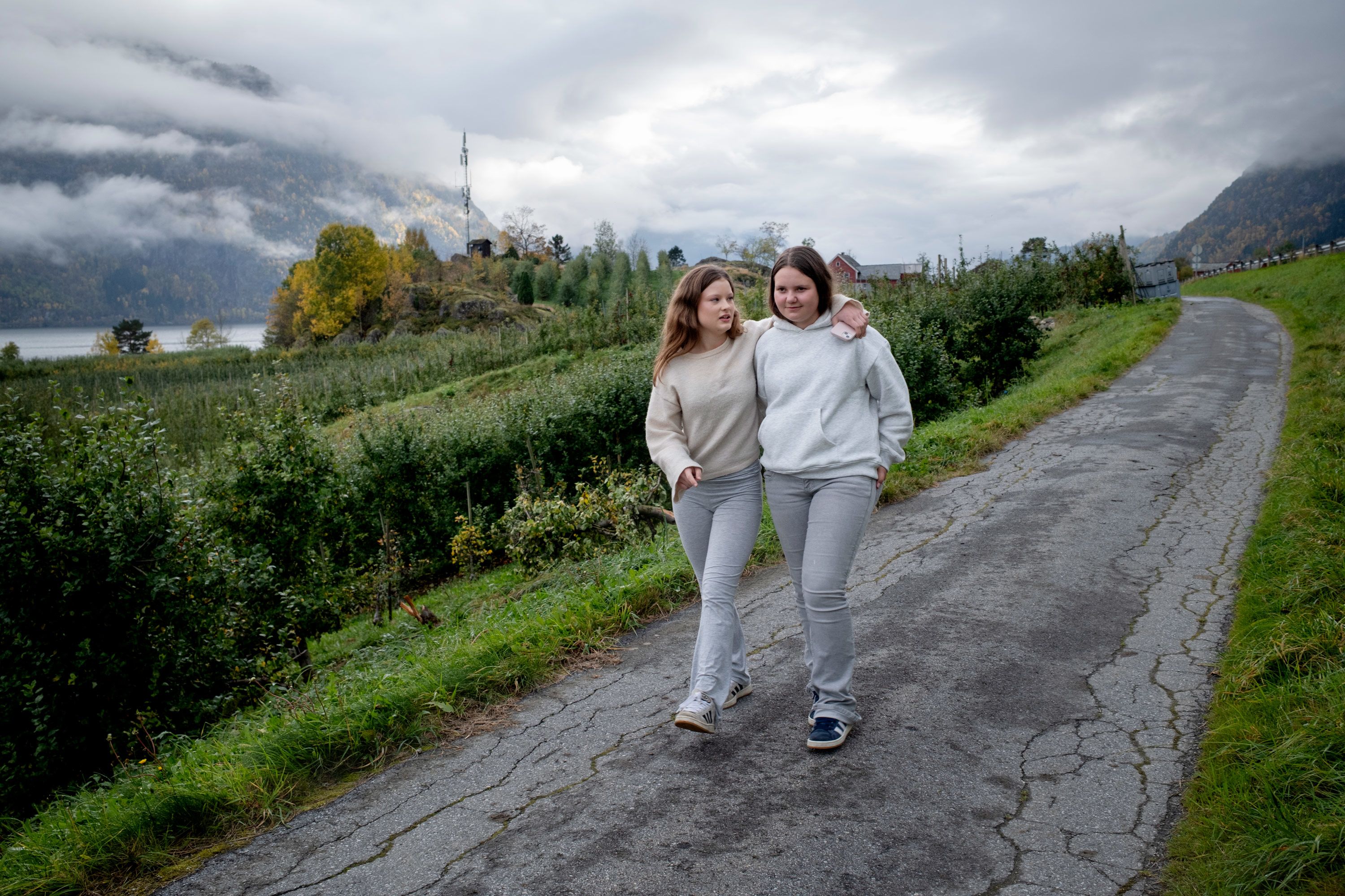 Emma og en venninne går på en gangvei omringet av frodig, grønn natur.