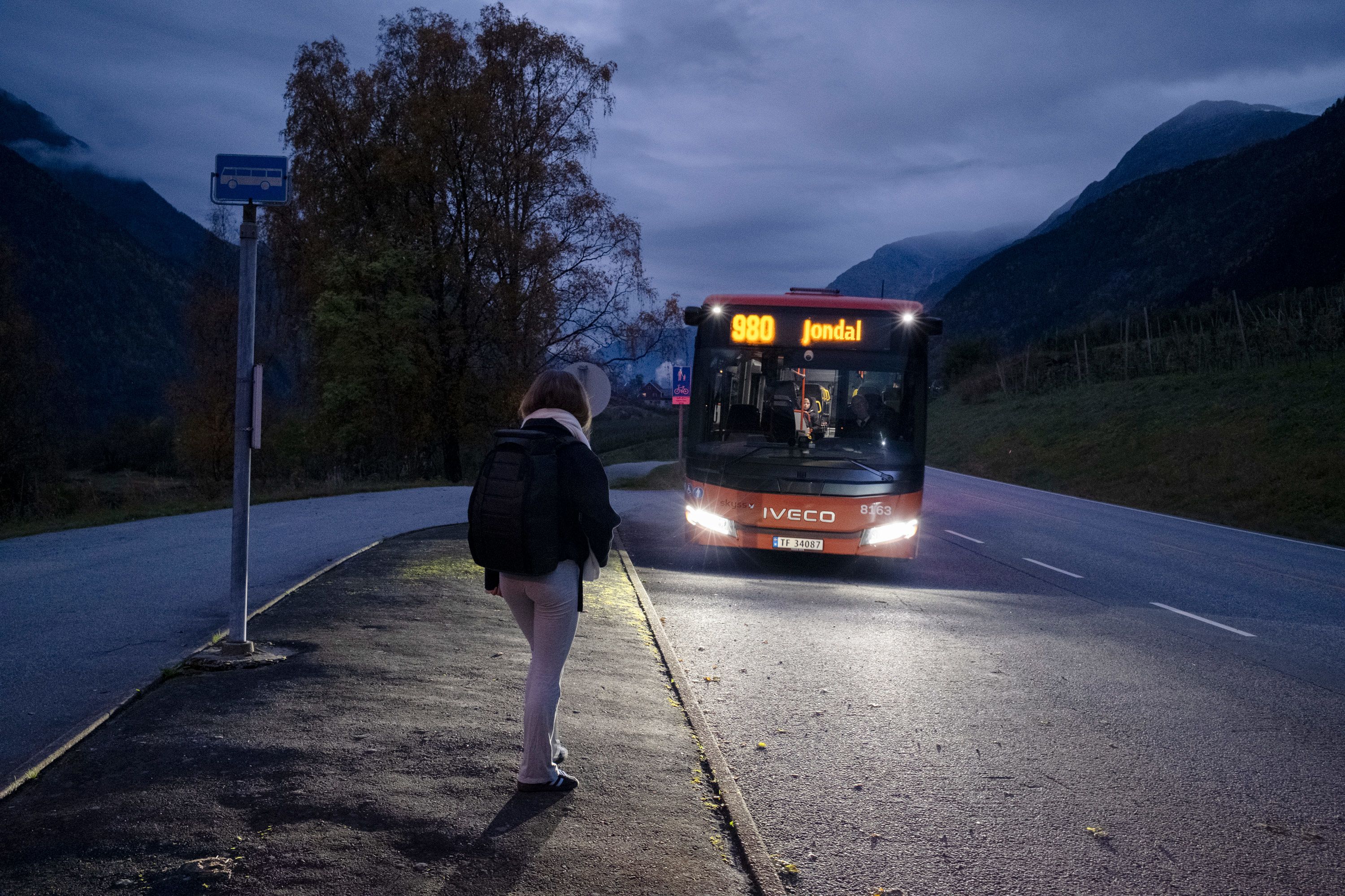 Emma står på busstoppet og venter på den røde bussen til Jondal..