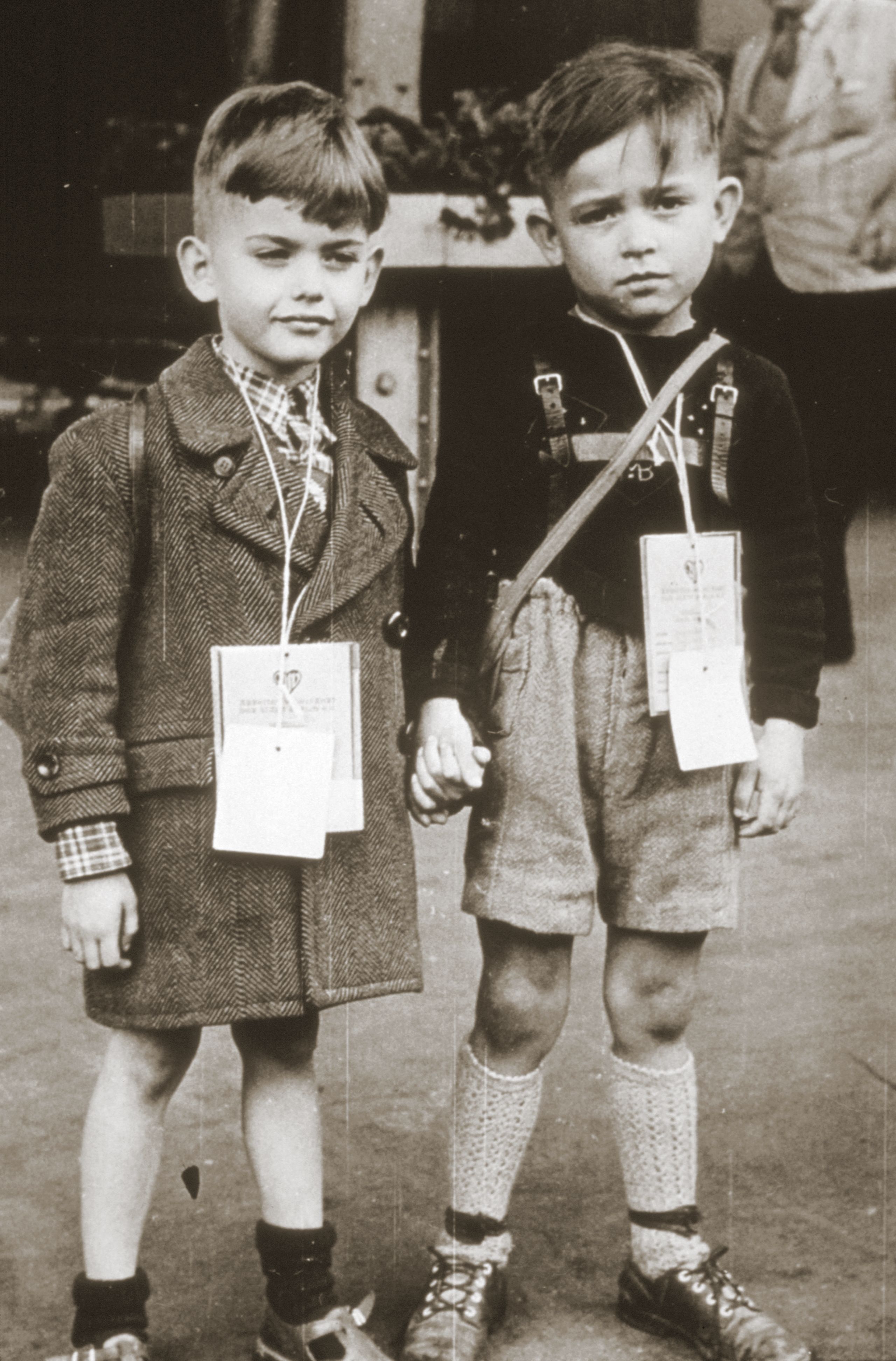 Sort hvitt arkivbilde fra 1948 viser to små gutter som holder hender og har identifikasjonspapirer rundt halsen.