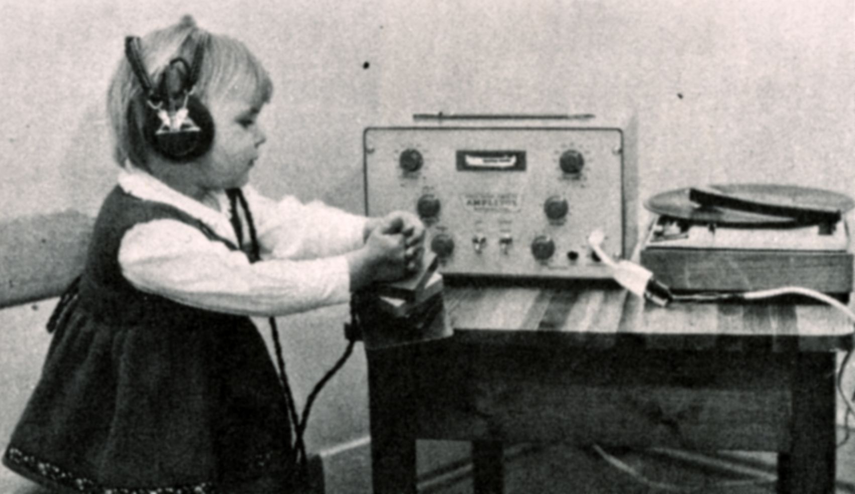 Sorthvitt bilde som viser ei lita jente med et radioapparat. Hun har på seg hodetelefoner.
