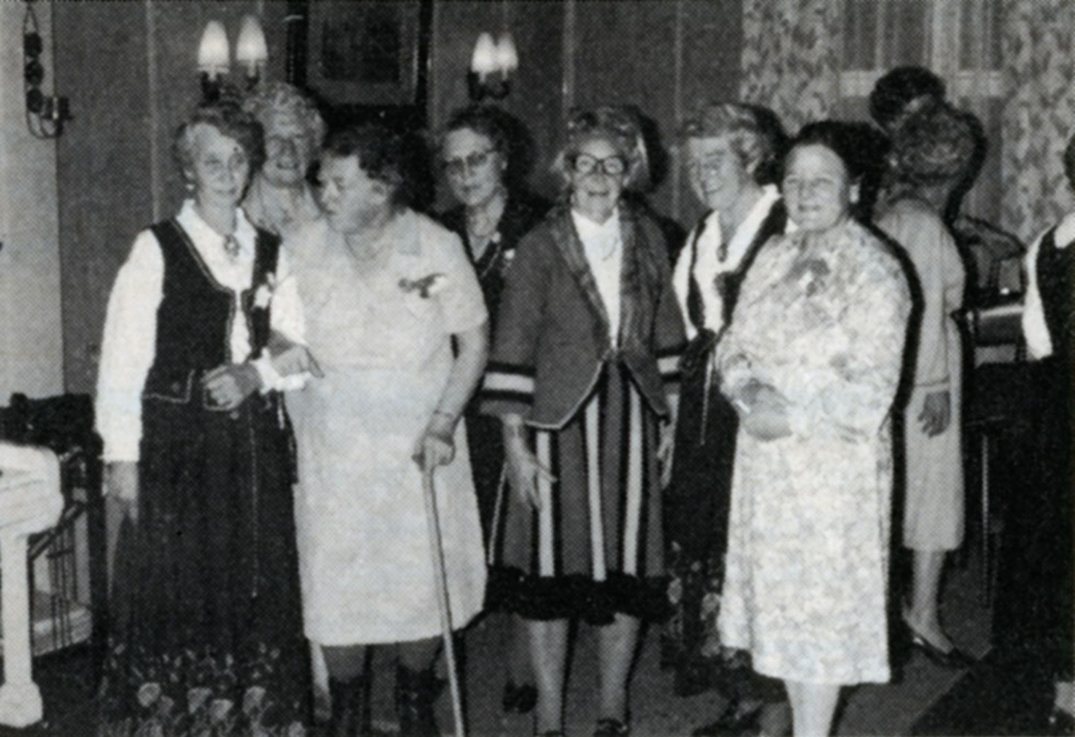 Sorthvitt bilde fra 1950 viser en gruppe eldre kvinner samlet i et lokale. De har på seg bunader og kjoler.