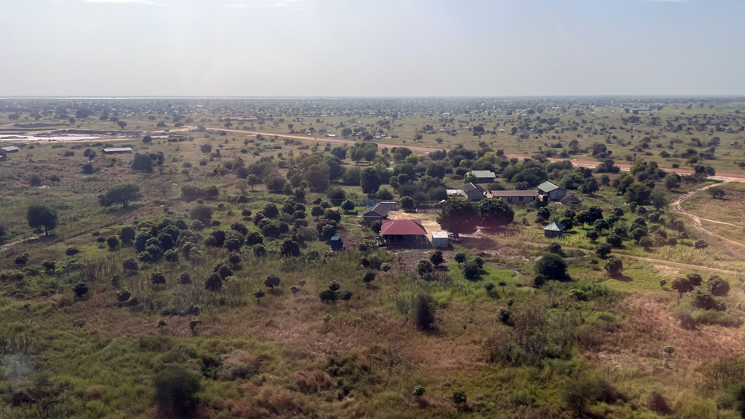 Landskapsbilde av et område i Sør-Sudan som viser hus og vegetasjon.