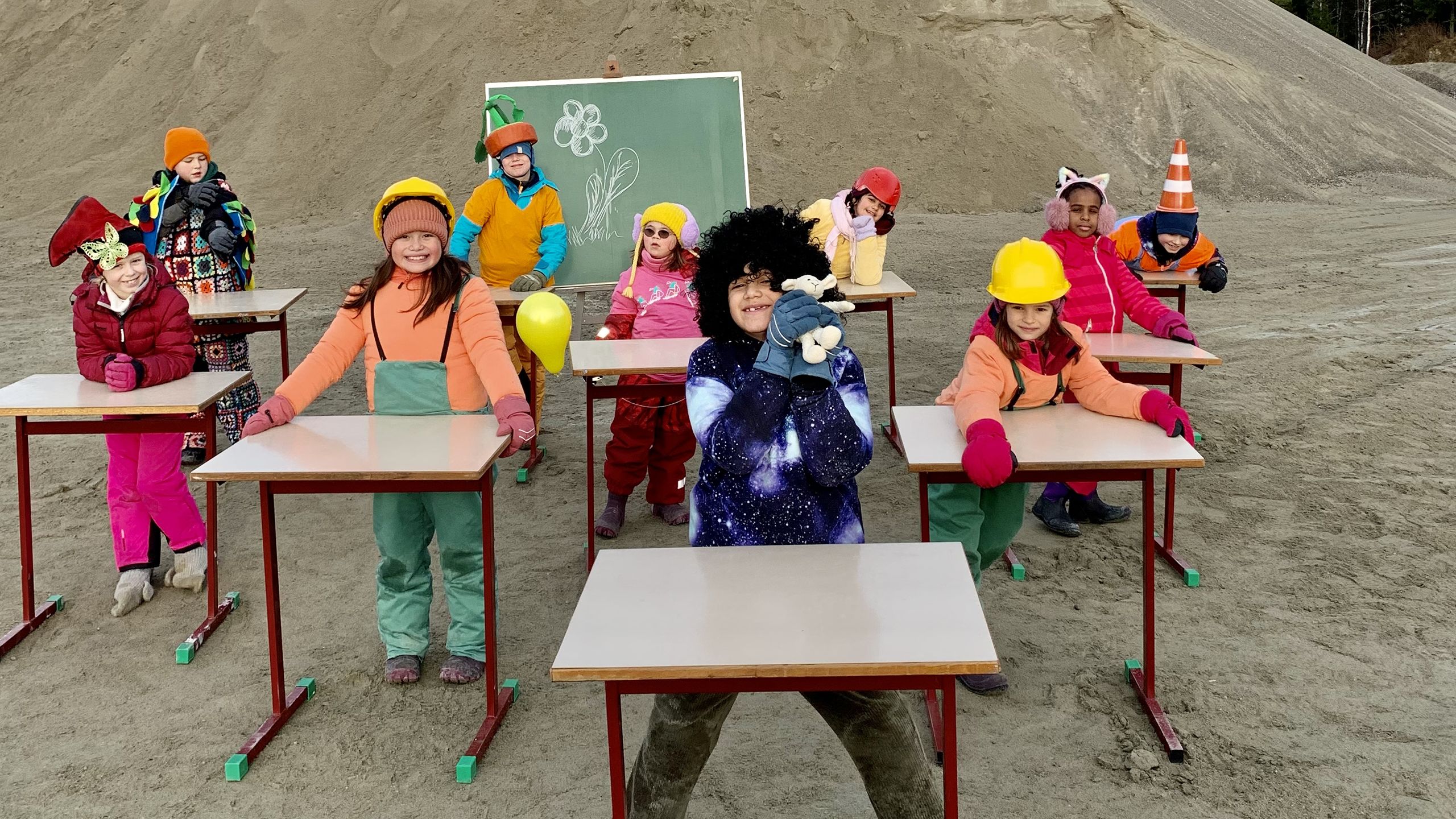 Fargerike barn på skolepulter utendørs.